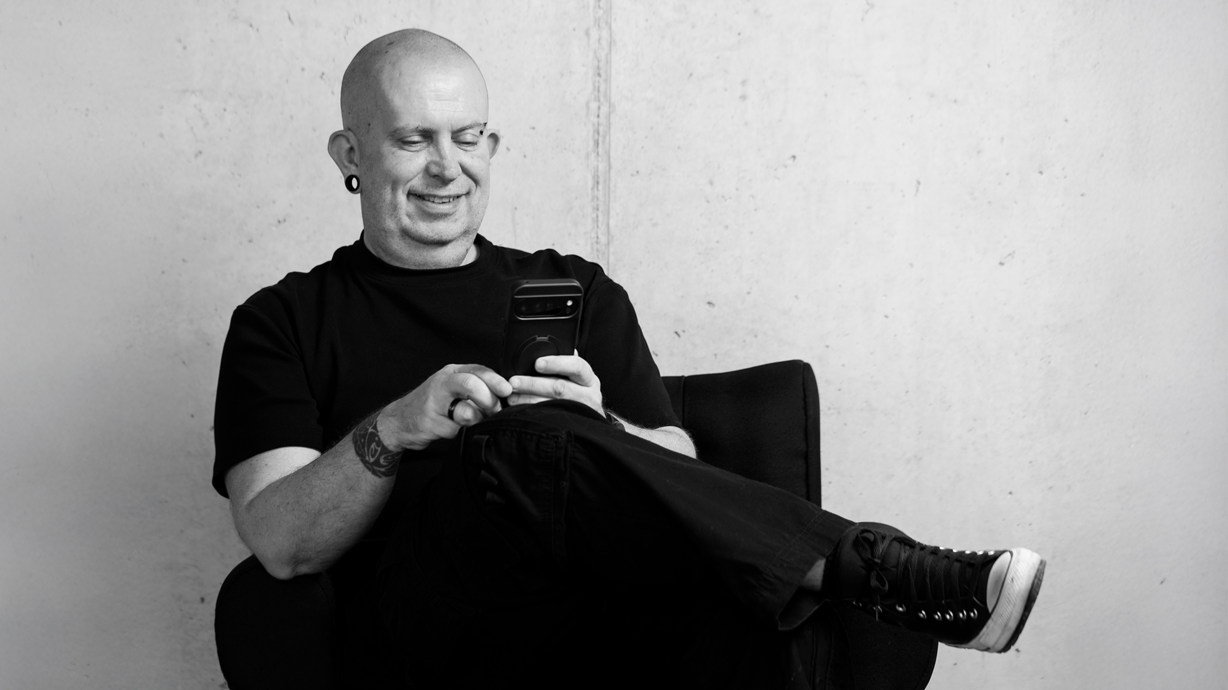 Walter Mlcak sitzen auf einem Stuhl mit seinem Smartphone